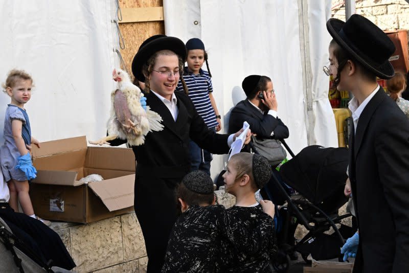 Israeli police are urging the public to carry guns to synagogues during Yom Kippur due to increasing terror threats. An Ultra-Orthodox Jewish man swings a chicken over the heads of boys during the ancient ritual Kapparot in Mea Shearim in Jerusalem on Thursday. Photo by Debbie Hill/UPI