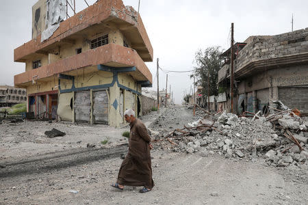 A displaced Iraqi man walks past damaged buildings as the battle between the Iraqi Counter Terrorism Service and Islamic State militants continues nearby, in western Mosul, Iraq, April 23, 2017. REUTERS/Marko Djurica