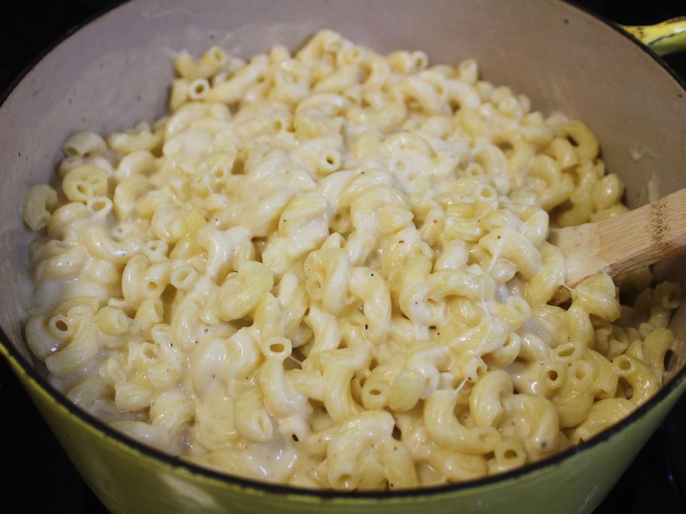 macaroni mixed with cheese sauce and a wooden spoon