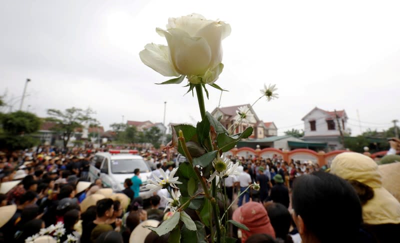 Ambulances carrying the bodies of John Hoang Van Tiep and John Nguyen Van Hung, victims who were found dead in the back of a British truck last month, are surrounded by relatives and villagers in front of a church in Nghe An province