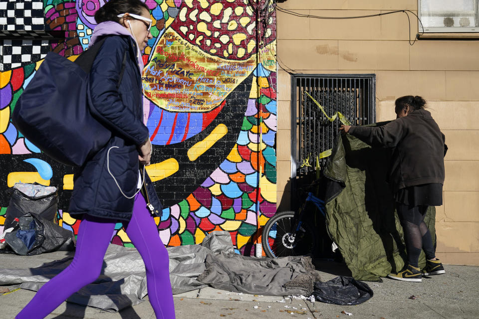 Victoria Solomon, right, hangs her belongings to dry after several days of rain in San Francisco, Monday, Dec. 12, 2022. Police harass her on a regular basis, she says, and San Francisco city workers have confiscated her belongings at least five times this year in tent cleanups. (AP Photo/Godofredo A. Vásquez)