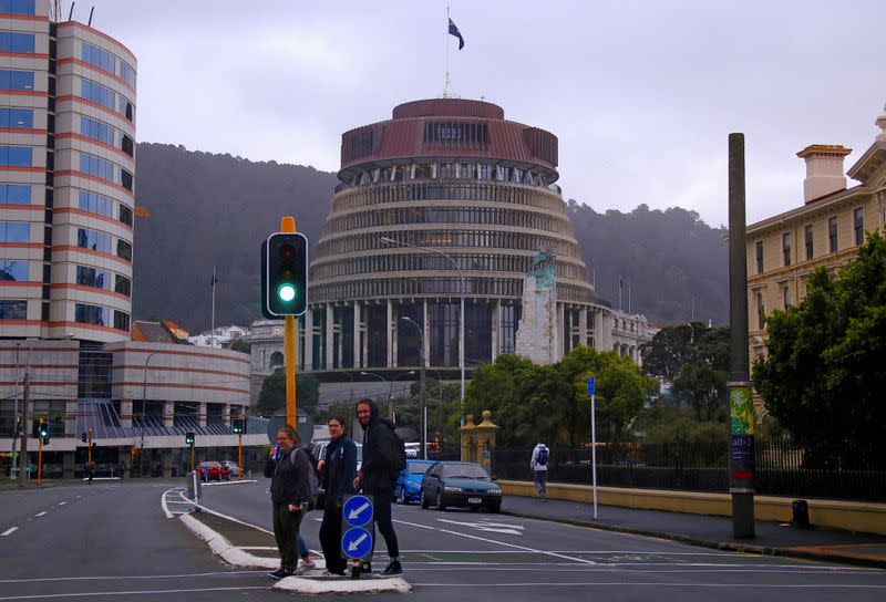 Pedestrians walk across a road in front of the New Zealand parliament building known as the Beehive in central Wellington, New Zealand