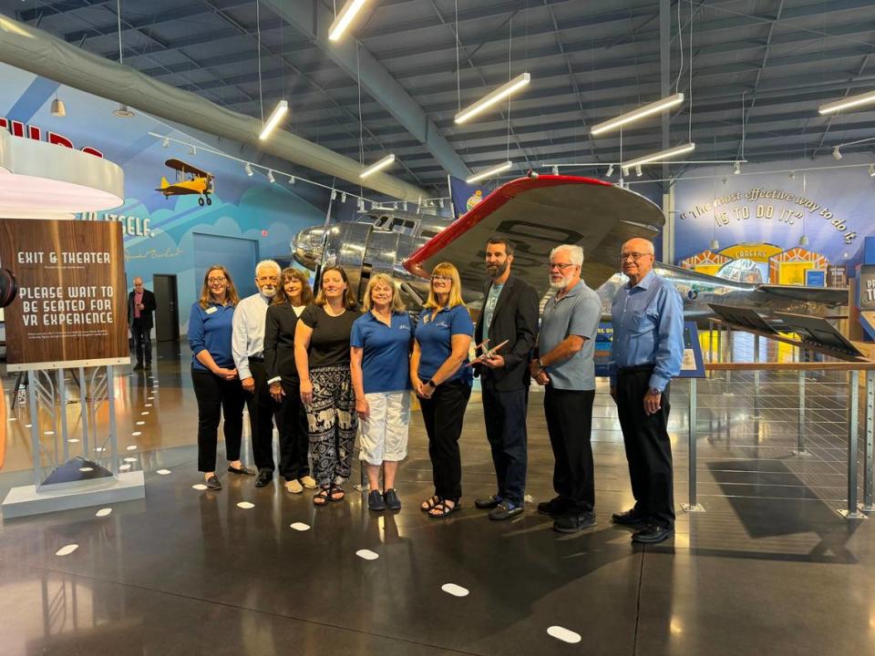 Speakers, along with staff from the Amelia Earhart Hangar Museum, pose for a photo in front of Muriel, the museum's Lockheed Electra 10-E.  Speakers gathered for a tour of the museum on Friday morning.