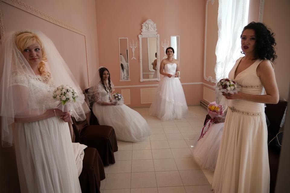 Brides wait to attend a wedding ceremony of several pairs in the center of Berdyansk, in territory under the government of the Donetsk People's Republic, eastern Ukraine, Saturday, April 30, 2022. This photo was taken during a trip organized by the Russian Ministry of Defense. (AP Photo)