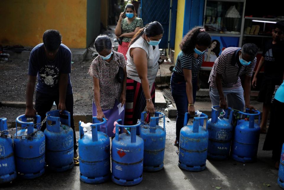 People carry their empty cylinders as they move in a queue to buy domestic gas at a distribution centre (Reuters)