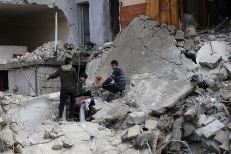 Boys stand amidst rubble of damaged buildings in the northern Syrian city of al-Bab, Syria March 13, 2017. REUTERS/Khalil Ashawi