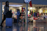 Passenger walk by the Shanghai Disney flagship store at the Hongqiao Railway Station in Shanghai, China, Monday, Oct. 14, 2019. China's trade with the United States fell by double digits again in September amid a tariff war that threatens to tip the global economy into recession. (AP Photo/Andy Wong)