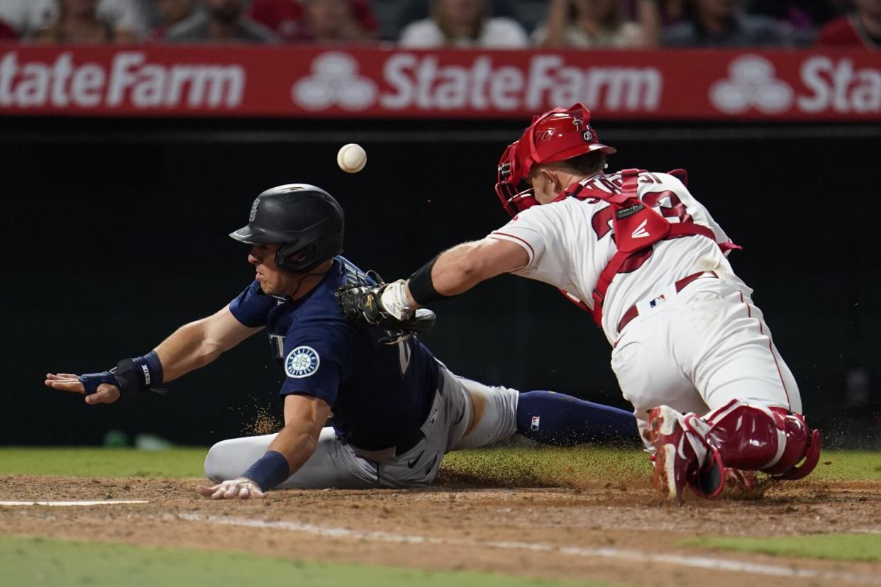 Seattle Mariners' Dylan Moore scores past Angels catcher Max Stassi..