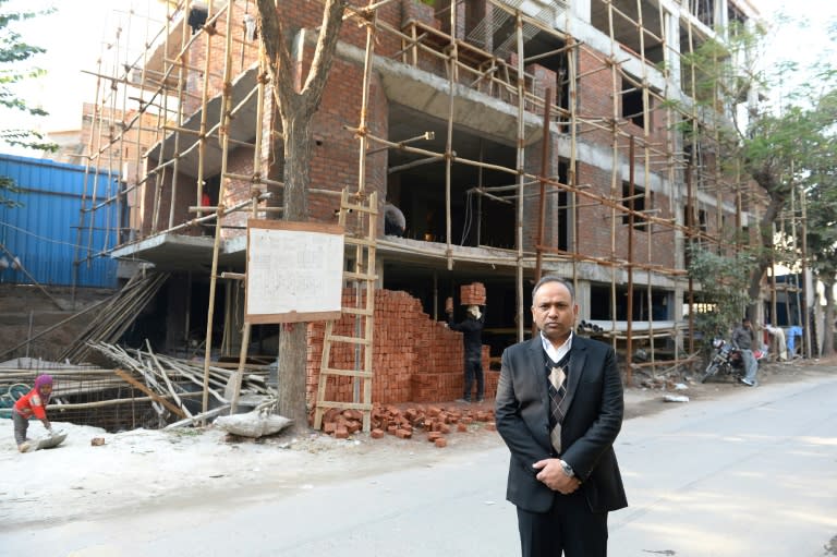 Indian lawyer Naresh Gupta poses outside an under-construction building in New Delhi