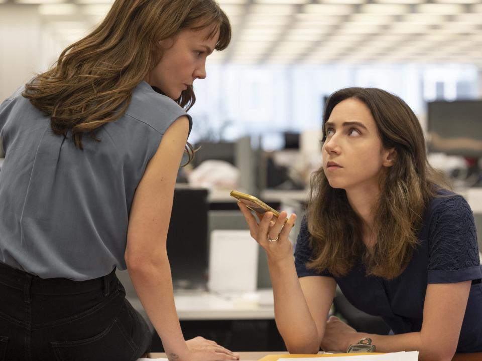 Carey Mulligan and Zoe Kazan sitting on a desk listening to a phone