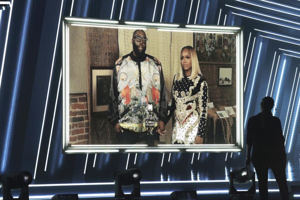 Killer Mike and Shana Render are shown on a large video screen holding hands.
