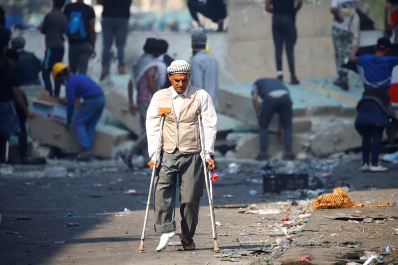 A demonstrator walks on a crutch as he takes part on the ongoing anti-government protests in Baghdad