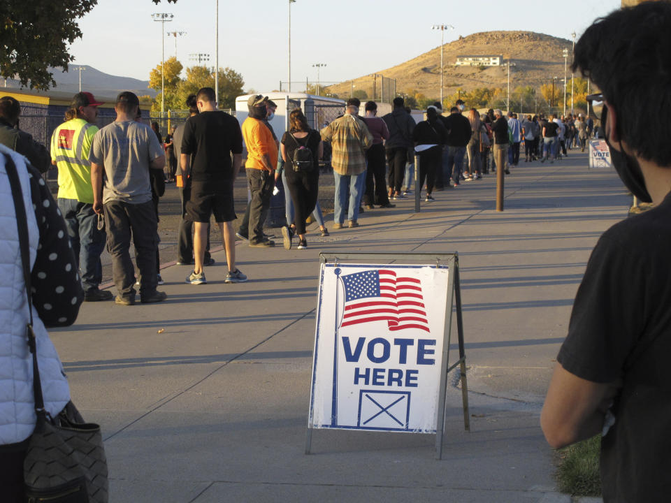 About 100 mostly masked northern Nevadans waiting to vote in person at Reed High School in Sparks about two hours before the polls closed Tuesday in the western battleground state. Mail-in ballots also were sent to active registered statewide, including Reno-Sparks, where registration is split almost evenly among the two major parties (AP Photo/Scott Sonner)