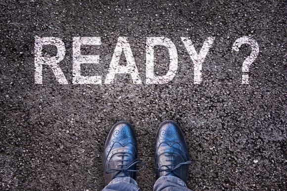 looking down at a man's feet in wingtip shoes, with the question Ready written on the asphalt next to them