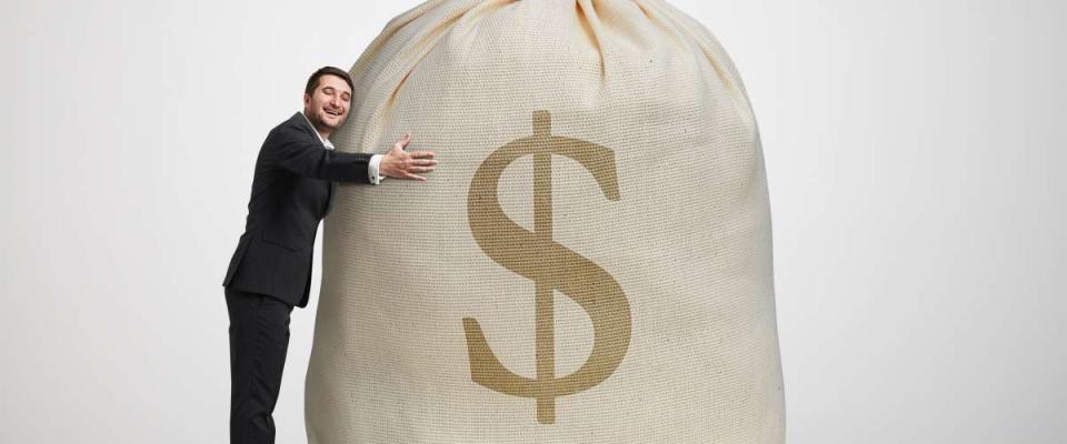 man hugging a large bag of money