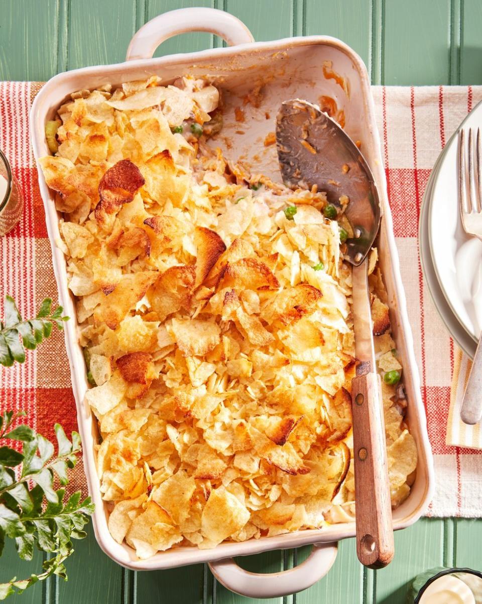 tuna noodle casserole in a cream colored rectangle baking dish with a serving spoon