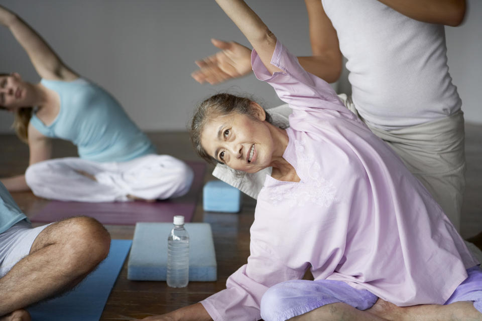 middle aged woman with perimenopause doing a yoga stretch on the ground