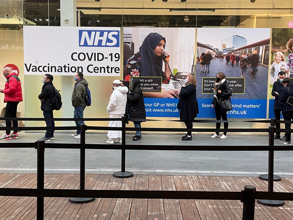 People queue at a COVID Vaccination Centre at the Westfield shopping centre in Stratford, east London, as the coronavirus booster vaccination programme continues across the UK. Despite the ramping-up of the booster programme, experts said it would not help in terms of hospitals admissions in the near future, as many would be people who are infected now before immunity has had time to build. Picture date: Monday December 20, 2021. (Photo by Jonathan Brady/PA Images via Getty Images)