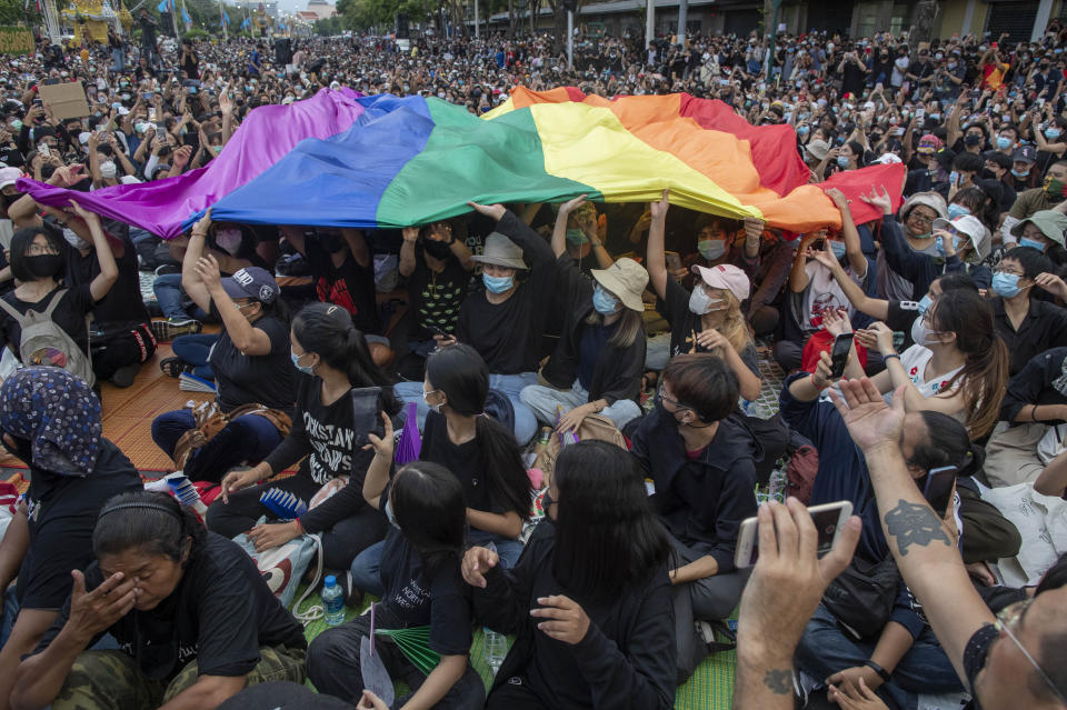 Pro-democracy activities display a LGBT flag during a protest at Democracy Monument in Bangkok, Thailand, Sunday, Aug, 16, 2020. Protesters have stepped up pressure on the government demanding to dissolve the parliament, hold new elections, amend the constitution and end intimidation of the government's opponents. (AP Photo/Gemunu Amarasinghe)