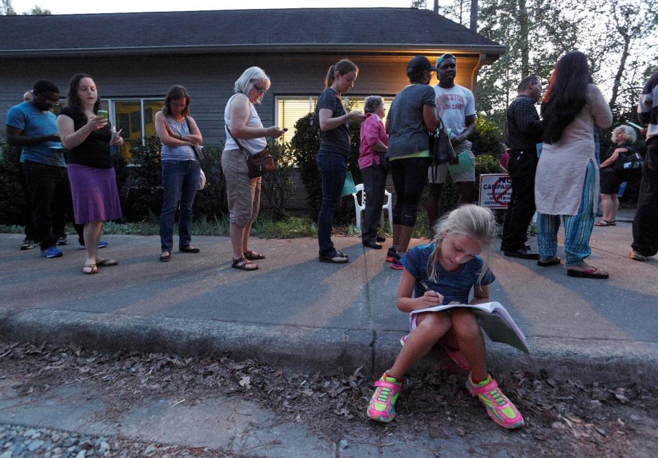 Louisa Weinard, 9, works on her homework while her mother waits in a line at a polling station open into the evening as early voting for the 2016 general elections begins in Durham, North Carolina, U.S., October 20, 2016. REUTERS/Jonathan Drake