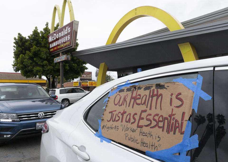 FILE - In this April 6, 2020, file photo, protesters stop momentarily at the McDonald's drive-thru, as they join fast-food workers protesting for a second day outside the restaurant in the Crenshaw district of Los Angeles. Across the country, the new, unexpected front-line workers of the pandemic — from grocery store and fast food workers to Instacart shoppers and Uber drivers — are taking action to protect themselves. (AP Photo/Damian Dovarganes)