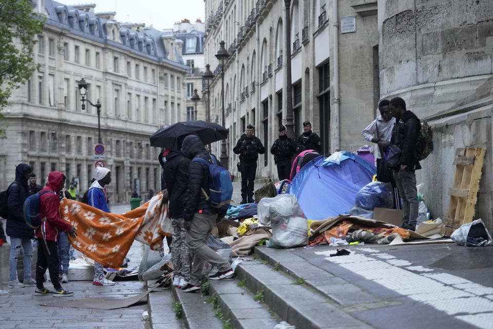 Miigrants pack their belongings while being evicted from a makeshift camp, Tuesday, April 30, 2024 in Paris. Similar operations are carried out by the police authorities on a daily basis in the months leading to the Olympics. (AP Photo/Michel Euler)