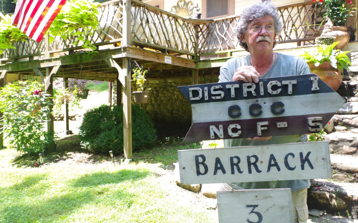 Dennis Coffey outside his house with a sign he has preserved from the now-destroyed Civilian Conservation Corp camp - Emma Yeomans