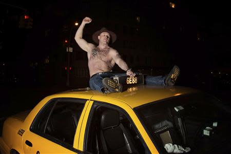 A taxi driver named Darek poses on top of his cab for the NYC Taxi Drivers 2014 Calendar in this handout received December 10, 2013. REUTERS/Shannon McLaughlin/NYC Taxi Drivers 2014 Calendar/Handout via reuters