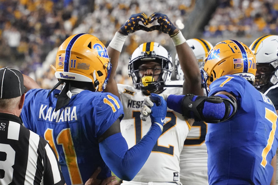 West Virginia tight end CJ Donaldson (12) celebrates in front of Pittsburgh linebacker Bangally Kamara (11) and linebacker SirVocea Dennis (7) after scoring a touchdown during the second half of an NCAA college football game, Thursday, Sept. 1, 2022, in Pittsburgh. (AP Photo/Keith Srakocic)