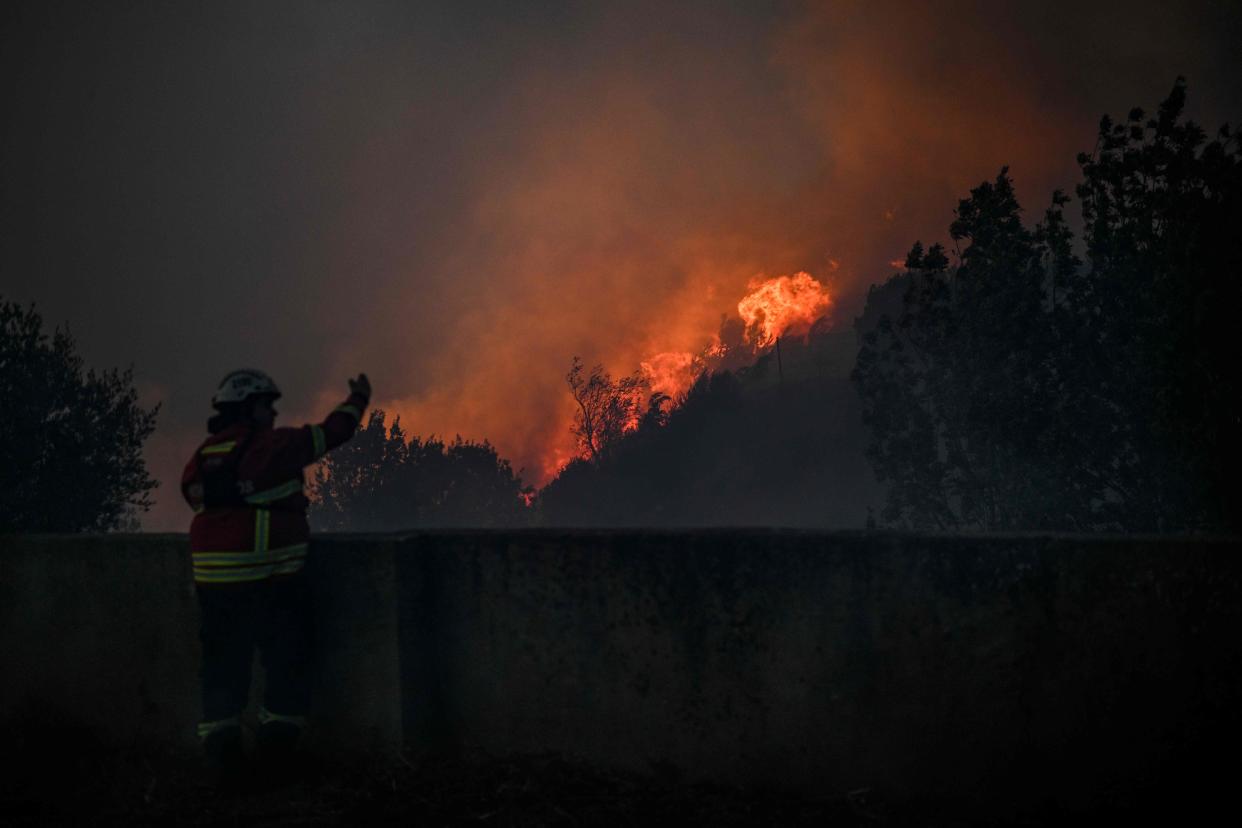 A firefighter watches the progression of a wildfire as it approaches Zambujeiro village in Cascais (AFP via Getty Images)