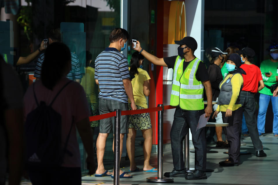 SINGAPORE - MAY 12:  A man wearing a protective mask has his temperature taken before entering a McDonald's fast food restaurant on May 12, 2020 in Singapore. The Singapore government starts easing lockdown measures today to allow businesses such as selected food retail outlets, laundry services, barbers, home-based food businesses and pet supplies stores to resume operations, while still maintaining the partial lockdown until June 1 to bring down the coronavirus (COVID-19) cases within the community.  (Photo by Suhaimi Abdullah/Getty Images)