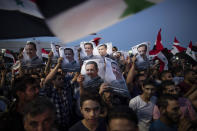 Syrian President Bashar Assad supporters hold up national flags and pictures of Assad as they celebrate at Omayyad Square, in Damascus, Syria, Thursday, May 27, 2021. (AP Photo/Hassan Ammar)