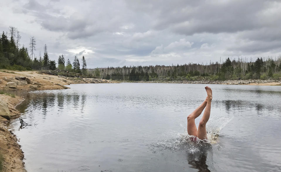 A man jumps headfirst into the Oderteich dam in the Harz National Park near Oderbrueck, Germany, Saturday, May 23, 2020. After the easing of measures to contain the Corona pandemic, numerous tourists came to the Harz mountains at the weekend. (Julian Stratenschulte/dpa/dpa via AP)