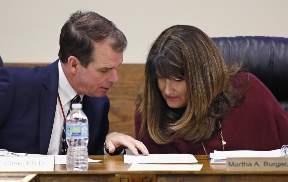 Terry Cline, left, Oklahoma Commissioner of Health, and Martha A. Burger, right, president of the Oklahoma State Board of Health, put their heads together during a meeting in Oklahoma City, Tuesday, Dec. 13, 2016. Oklahoma plans to force hospitals, nursing homes, restaurants and public schools to post signs inside public restrooms directing pregnant women where to receive services as part of an effort to reduce abortions in the state. (AP Photo/Sue Ogrocki)