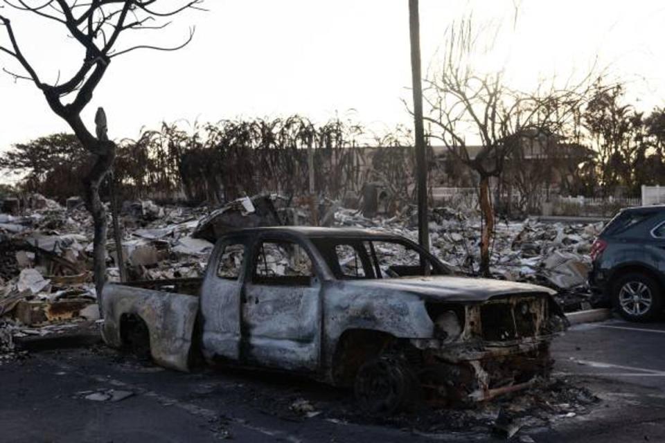 A burnt out car lies in the driveway of charred apartment complex in the aftermath of a wildfire in Lahaina, western Maui, Hawaii on 12 August (AFP via Getty Images)