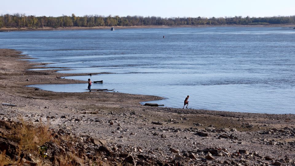 People walk along the banks of the Mississippi River, which has seen record low water levels, in Grand Tower, Illinois, November 2, 2022.    - Evelyn Hockstein/Reuters