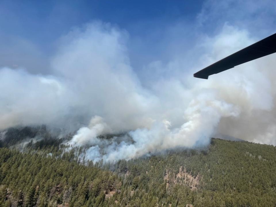 In this photo provided by the New Mexico National Guard, a New Mexico National Guard Aviation UH-60 Black Hawk flies as part of firefighting efforts, dropping thousands of gallons of water with Bambi buckets from the air on the Calf Canyon/Hermits Peak fire in northern New Mexico on Sunday, May, 1, 2022. Thousands of firefighters are battling destructive wildfires in the Southwest as more residents are preparing to evacuate. (New Mexico National Guard via AP)