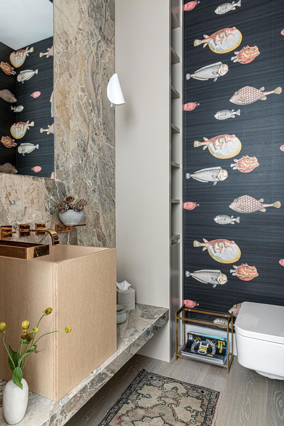 Shea took a more whimsical approach in the guest bathroom, whose walls are all clad in a fun Cole & Son wallpaper. The goal was to optimize for form and function, which explains the giant wood basin that serves as a unique take on a sink. On the opposite wall, she installed a hidden floor-to-ceiling cabinet for linen storage.