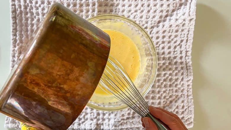 Pouring butter butter and lemon juice from saucepan into egg yolks and sugar to temper with whisk