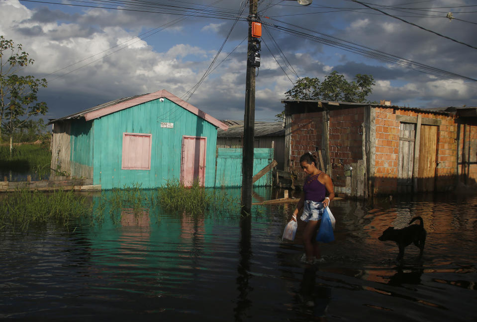 A woman walks on a street flooded by the rise of the Negro river in Iranduba, Amazonas state, Brazil, Monday, May 23, 2022. The Amazon region is being hit hard by flooding with 35 municipalities that are facing one of their worst floods in years and the water level is expected to rise over the coming months. (AP Photo/Edmar Barros)