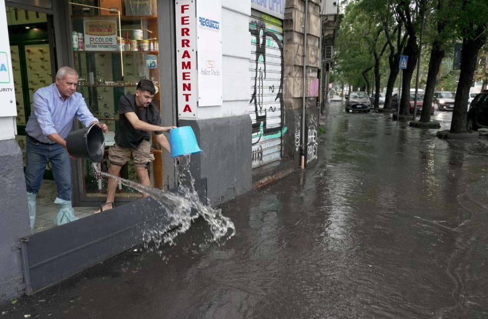 Residents and business owners clear floodwaters following heavy rainfall on the island of Sicily (REUTERS)