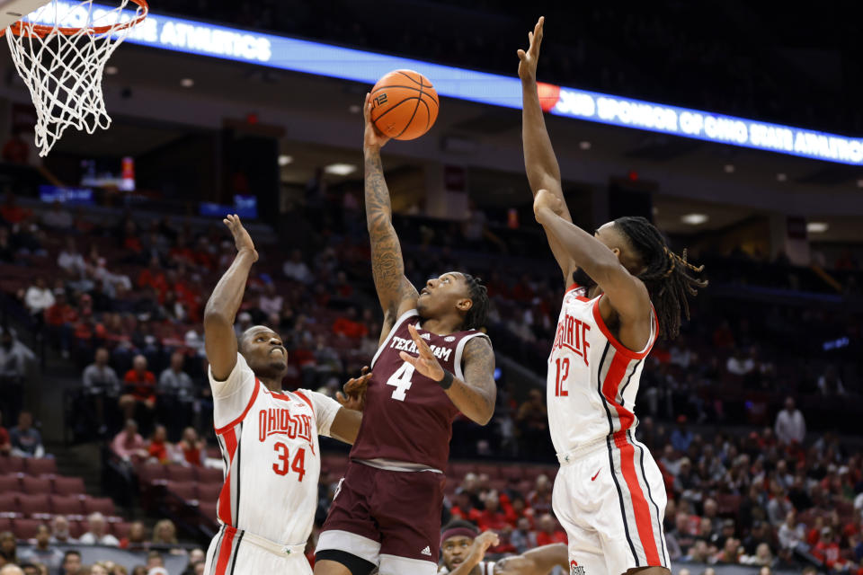 Texas A&M Guard Wade Taylor, center, shoots between Ohio State center Felix Okpara, left, and guard Evan Mahaffey, right, during the first half of an NCAA college basketball game in Columbus, Ohio, Friday, Nov. 10, 2023. (AP Photo/Paul Vernon)