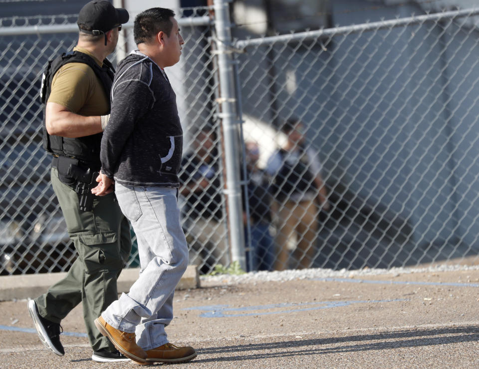 A man is taken into custody as U.S. immigration officials raided the Koch Foods Inc., plant in Morton, Miss., Wednesday, Aug. 7, 2019. U.S. immigration officials raided several Mississippi food processing plants on Wednesday and signaled that the early-morning strikes were part of a large-scale operation targeting owners as well as employees. (AP Photo/Rogelio V. Solis)