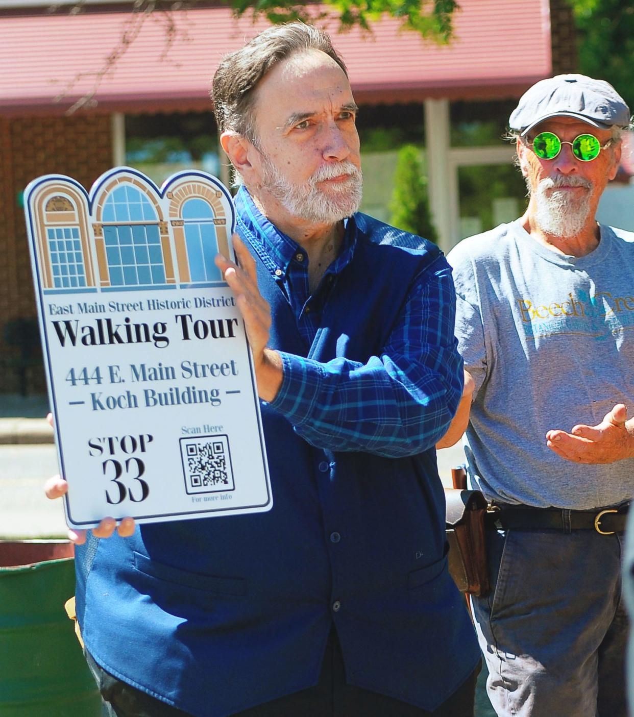 Robb Hyde holds a sign Saturday, June 15, 2024, similar to the ones that each stop of the East Main Street Historic District Walking Tour in downtown Alliance will display. Smart phones can scan the QR code on the signs to receive information about the particular numbered property and the history of the city.