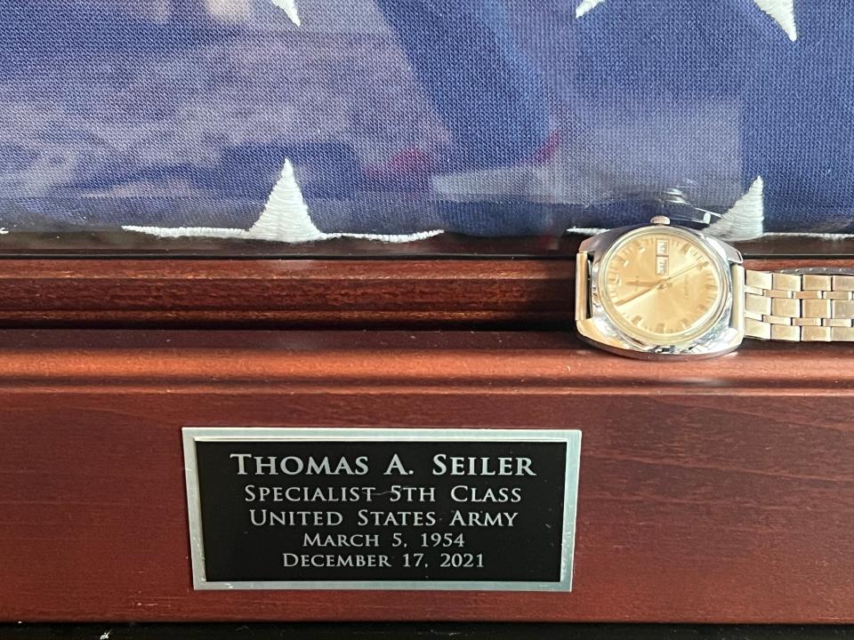 A returned Timex watch next to a military flag.