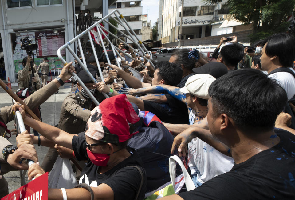 Anti-government protesters push a metal barrier into inside of the Samranrat police station in Bangkok, Thailand, Friday, Aug, 28, 2020. The protesters tussled with police on Friday as 15 of their movement leaders turned up at a police station to answer a summons linked to demonstrations denouncing the arrests. (AP Photo/Sakchai Lalit)