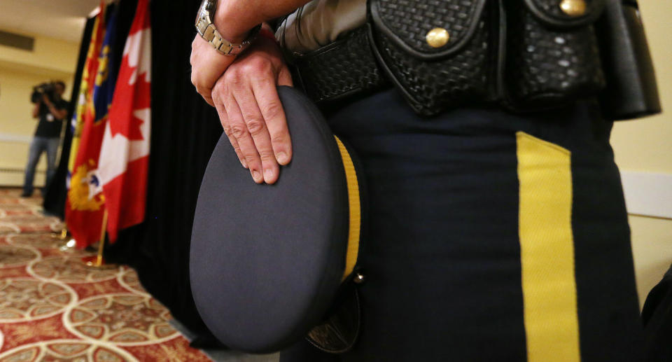 A Mountie holds his hat during a news conference. (Getty)