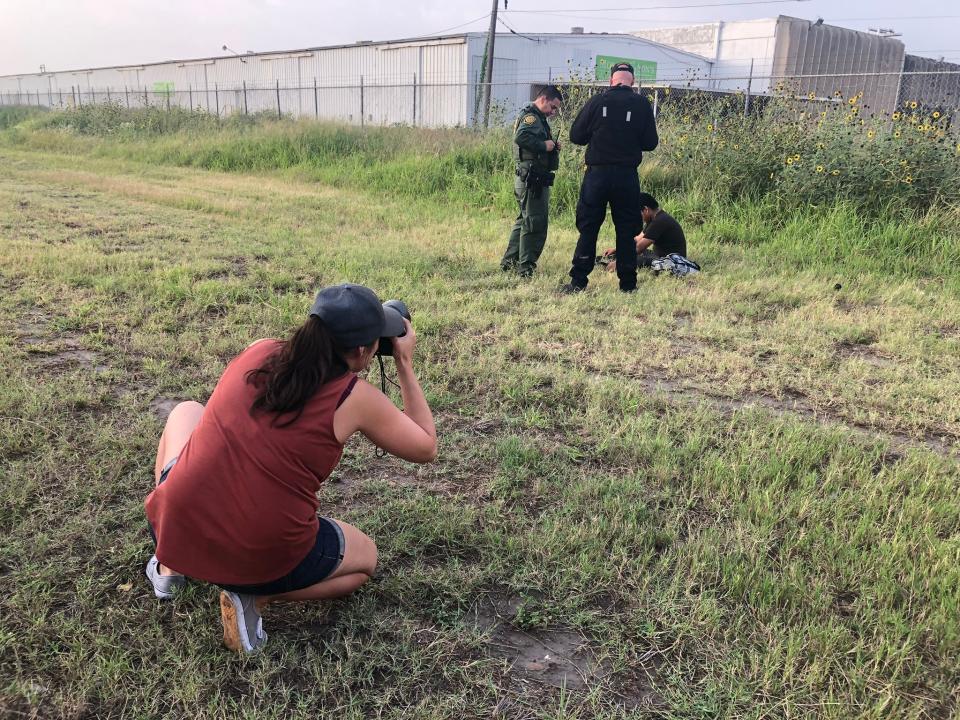 MCALLEN, Texas – Sandy Hooper takes pictures of a migrant being detained by Border Patrol agents in McAllen, Texas.