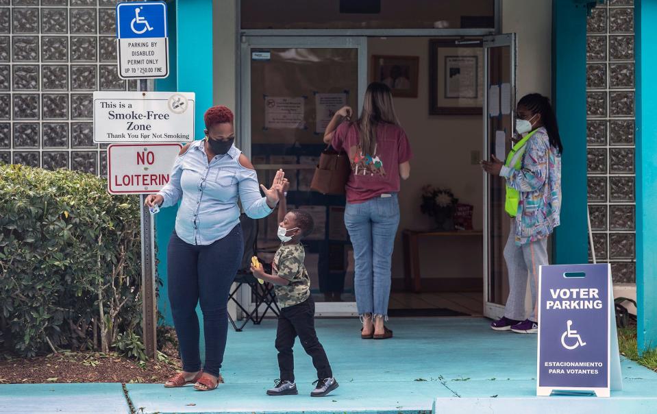 Vashonte King (left), of Vero Beach, Fla., gives a high-five to her son Ja-Haun Smith, 3, after voting at the Gifford Community Center on Election Day, Tuesday, Nov. 3, 2020, in Indian River County.