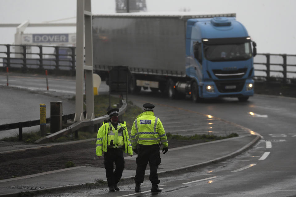 Police officers direct traffic at the entrance to the closed ferry terminal in Dover, England, Monday, Dec. 21, 2020, after the Port of Dover was closed and access to the Eurotunnel terminal suspended following the French government's announcement. France banned all travel from the UK for 48 hours from midnight Sunday, including trucks carrying freight through the tunnel under the English Channel or from the port of Dover on England's south coast. (AP Photo/Kirsty Wigglesworth)